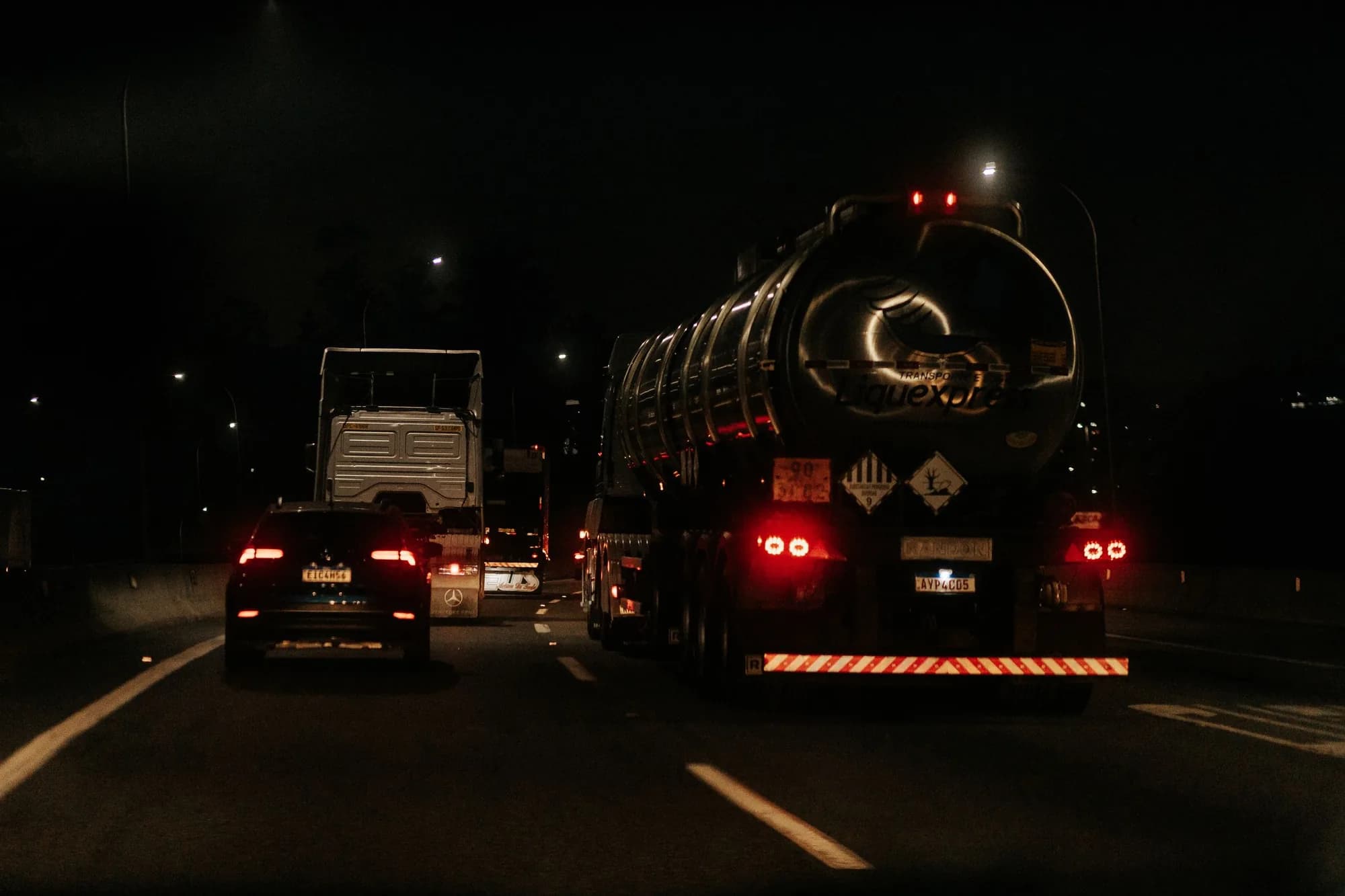 A tanker truck on a dark highway at night
